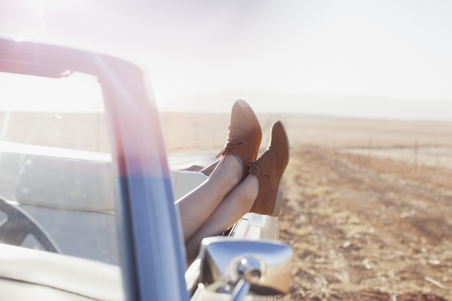 woman on road trip feet up convertible
