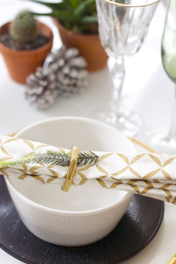 a place setting with gold elements, pinecones and pine needles for the holidays