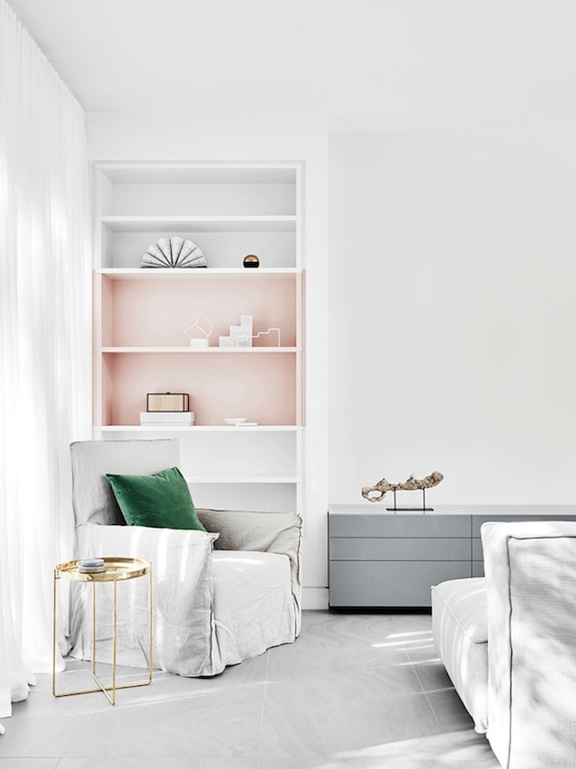 White room with a pink shelf and emerald green pillow