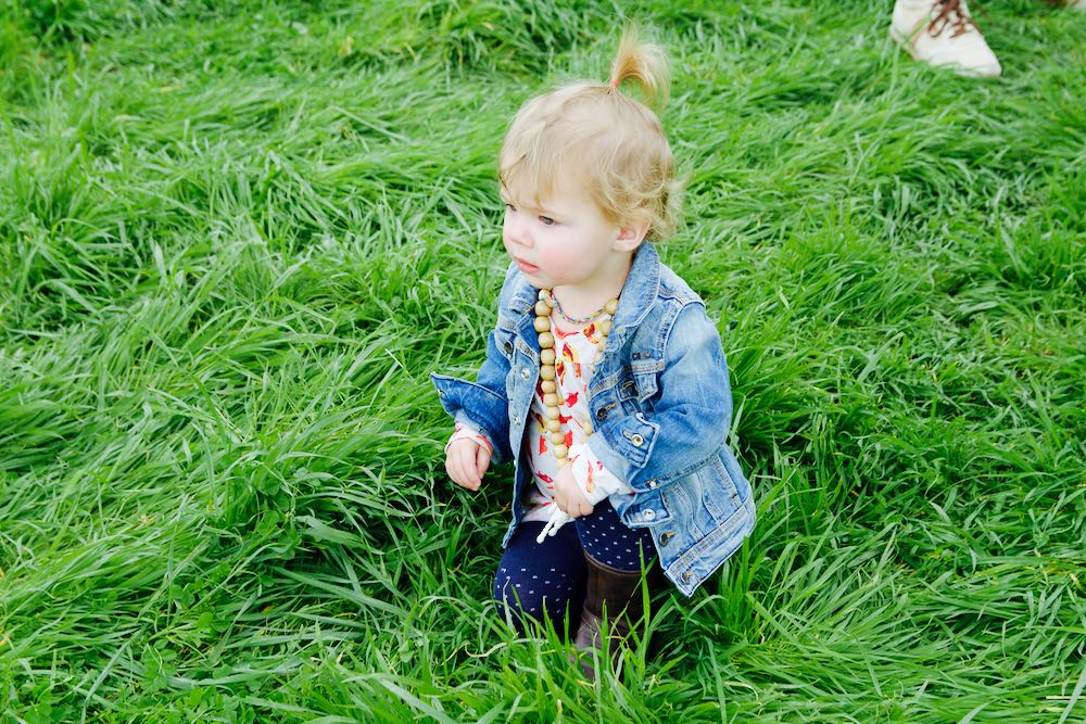 Baby in denim jacket sitting in the grass