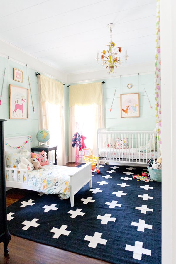 Nursery with a gorgeous rug and toddler bed and crib